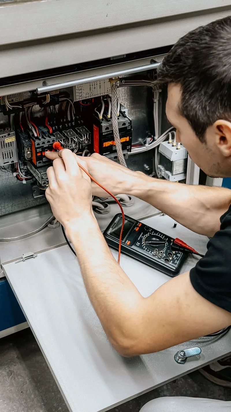 Electrician care măsoară cu multimetrul într-un tablou electric deschis